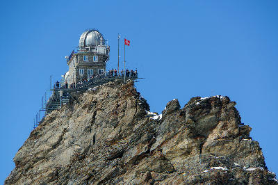 Sphinx Observatory on Jungfraujoch with viewing platform and Swiss flag on a rocky summit, Bernese Alps, Switzerland.