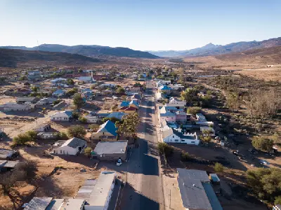 Drone view of Sutherland in the Northern Cape, showing the small Karoo town surrounded by open plains and mountain ridges beneath clear blue skies.