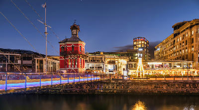 Clock Tower and pedestrian bridge at the V&A Waterfront illuminated at night in Cape Town, South Africa.