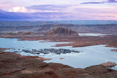 Wahweap Overlook view of Lake Powell marina in Page, Arizona, showing houseboats on the reservoir surrounded by layered red sandstone canyon formations.
