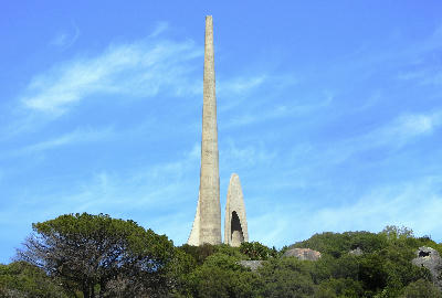 Tall concrete spires of the Afrikaans Language Monument on Paarl Mountain in South Africa’s Western Cape, surrounded by fynbos vegetation beneath a blue sky.