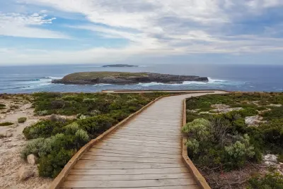 Wooden boardwalk leading through coastal vegetation towards the rocky Casuarina Islets and Southern Ocean at Cape du Couedic, Kangaroo Island.
