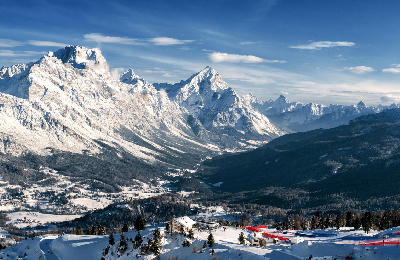 Aerial view of Cortina d’Ampezzo in the Dolomites, showing the mountain town set within a broad alpine valley in Belluno, northern Italy.