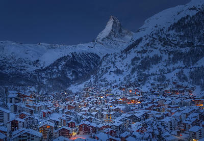 Zermatt village at blue hour with snow-covered chalets and the Matterhorn rising above the alpine valley, Switzerland