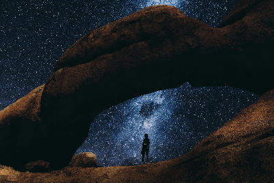 Silhouette of a person beneath the granite arch at Spitzkoppe under the Milky Way in Namibia.