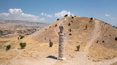 Ancient eagle-topped stone column in front of the burial mound at Karakuş Tumulus near Adıyaman, Turkey.