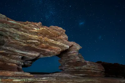 The layered sandstone arch of Nature’s Window illuminated beneath a dense star-filled night sky.