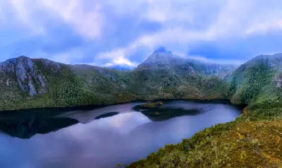 Dove Lake beneath cloud-covered Cradle Mountain and forested alpine slopes in Tasmania, Australia.