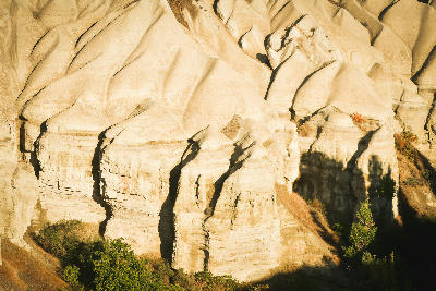 Sunlit white volcanic rock formations and eroded ridges in White Valley, Cappadocia, Turkey.