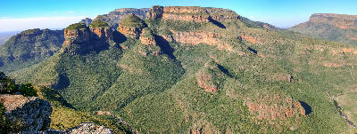 Panoramic view of the Three Rondavels and Blyde River Canyon in Mpumalanga, South Africa, showing layered sandstone cliffs and expansive canyon scenery.