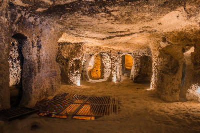 Illuminated underground chambers and connecting passages inside Kaymaklı Underground City in Cappadocia, Turkey.