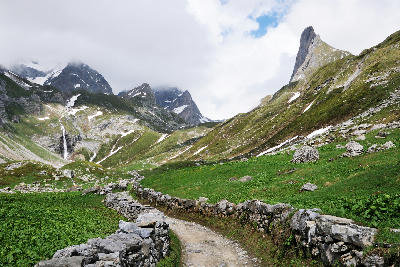 Mountain path leading through a green alpine valley toward Lac des Vaches in Vanoise National Park