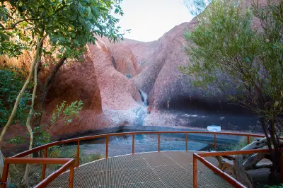 Mutitjulu Waterhole nestled beneath the red rock walls of Uluru, viewed from the Kuniya Walk lookout.