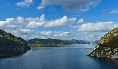 Lake Gordon surrounded by rocky shores, forested hills and distant mountains in southwest Tasmania, Australia.