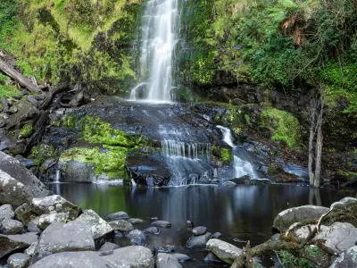 Water cascading over moss-covered rock into a pool at the base of Erskine Falls near Lorne, Victoria.