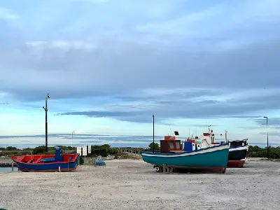 Colourful fishing boats on sandy ground near Struisbaai Harbour under overcast skies in the Western Cape.