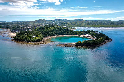 Aerial view of the volcanic crater lagoon near Ambatoloaka on Nosy Be island in Madagascar surrounded by tropical forest and turquoise coastal water.