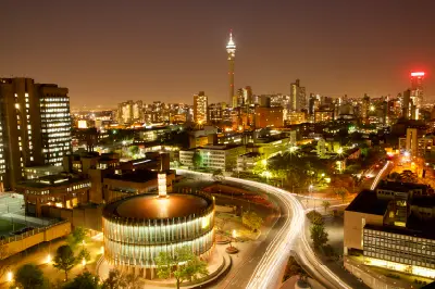 Night view of Johannesburg skyline from the Parktonian Hotel, featuring illuminated buildings, light trails and the Hillbrow Tower in Gauteng, South Africa.