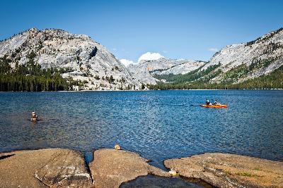 Kayakers on Tenaya Lake with granite domes and forest in Yosemite National Park