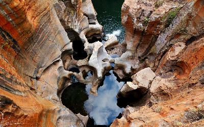 Close-up view of Bourke’s Luck Potholes in Mpumalanga, South Africa, showing smooth sandstone formations, circular erosion potholes, dark reflective pools and sculpted rock channels carved by flowing water.