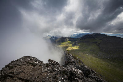 Rocky summit edge with low clouds drifting across Slættaratindur, the highest mountain on Eysturoy, Faroe Islands.