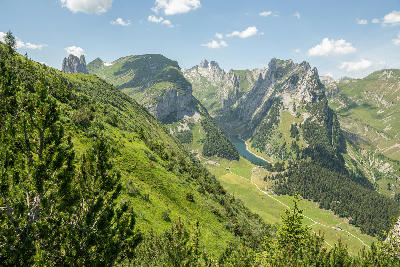 View across the Alpstein range toward Saxer Lücke, with steep ridgelines descending into a narrow alpine valley and lake below.