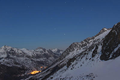 Night view of La Grave village lights in a mountain valley below La Meije, French Alps
