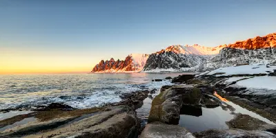 Sunset light on Okshornan peaks with foreground rock channels and tidal pools on Senja