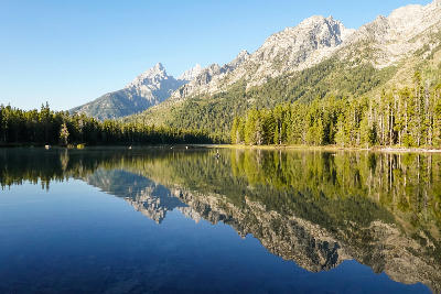 Jagged Teton Range peaks mirrored in calm String Lake with forest shoreline in Grand Teton National Park, Wyoming, USA.