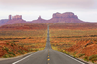 Straight desert highway leading toward sandstone buttes in Monument Valley, Utah–Arizona border, USA