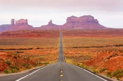 Straight desert highway leading toward sandstone buttes in Monument Valley, Utah–Arizona border, USA