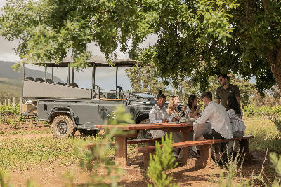 Visitors seated beside a safari-style vineyard vehicle during a wine tasting experience at Waterford Estate in Stellenbosch, Western Cape, South Africa.