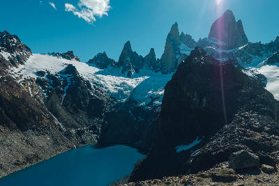 High viewpoint above Laguna de los Tres showing dark blue glacial lake and Mount Fitz Roy peaks in Patagonia, Argentina.