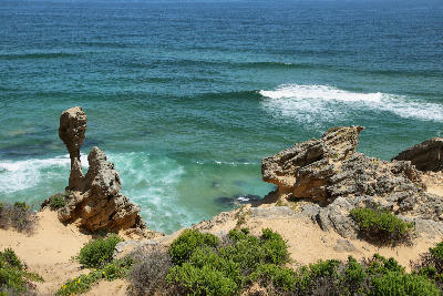 Sandstone sea stack and rugged coastal cliffs above turquoise ocean waves at Brenton-on-Sea near Knysna on South Africa's Garden Route.