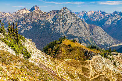 Hiking trail along Maple Pass ridge with golden alpine slopes and mountain peaks in North Cascades