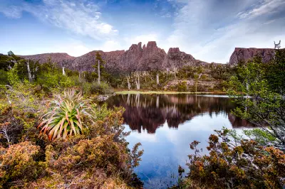 Mount Acropolis reflected in a still alpine tarn surrounded by native vegetation near Lake St Clair, Tasmania.