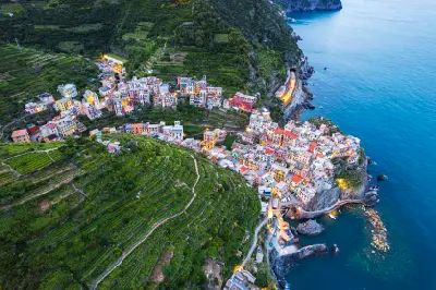 Aerial dusk view of Manarola, with illuminated colourful houses above the Ligurian Sea in Cinque Terre National Park, Italy.