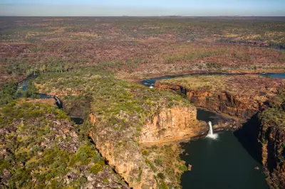 Aerial view of Mitchell Falls and Big Mertens Falls dropping into separate pools amid rugged sandstone cliffs and the vast Mitchell Plateau.