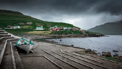 Small fishing boat on slipway with Elduvík village and church on Eysturoy, Faroe Islands.