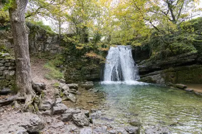 Janet's Foss waterfall cascading into a clear pool beneath autumn trees and limestone cliffs near Malham, North Yorkshire.