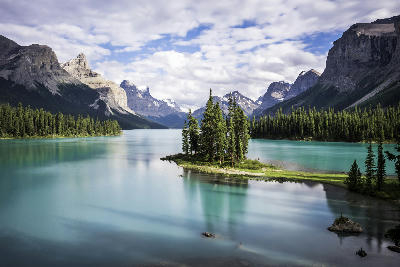 Spirit Island surrounded by turquoise Maligne Lake with mountain peaks in Jasper National Park