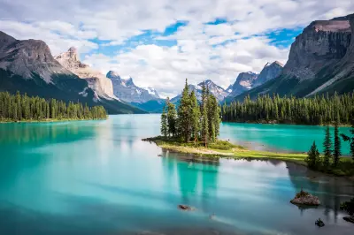 Spirit Island surrounded by turquoise Maligne Lake with mountain peaks in Jasper National Park