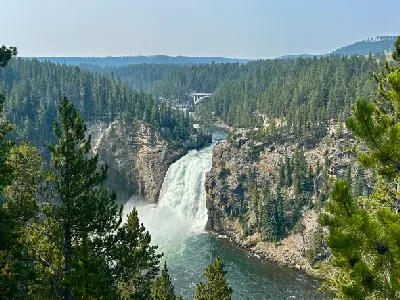 Upper Falls of the Yellowstone River with upstream bridge and forested canyon