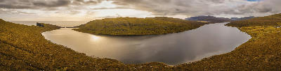 Panoramic view of Sørvágsvatn lake on Vágar Island, Faroe Islands, with the Atlantic Ocean visible beyond the coastal plateau.