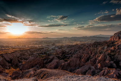 Sunset over Red Valley in Cappadocia, Turkey, with colourful volcanic rock formations, eroded ridges, and a dramatic sky glowing above the landscape.