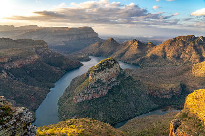 View of the Blyde River Canyon and Three Rondavels in Mpumalanga, showing towering cliffs, winding river bends, rugged mountain formations and dramatic canyon scenery in South Africa.