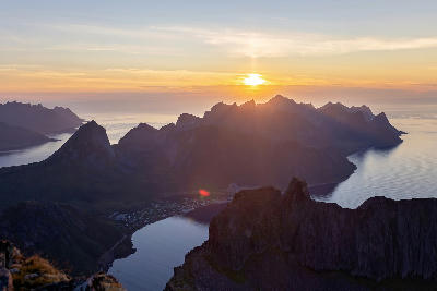 Grytetippen Senja Norway sunset view over fjords and rugged mountain ridges with coastal village below and open sea beyond.