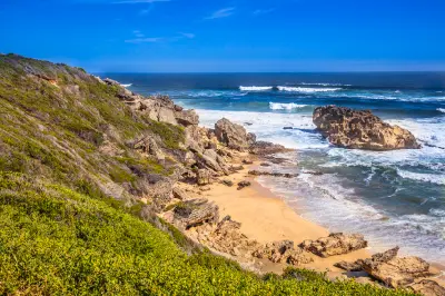 Rocky coastline and sandy coves at Brenton-on-Sea with waves breaking against cliffs on South Africa's Garden Route near Knysna.