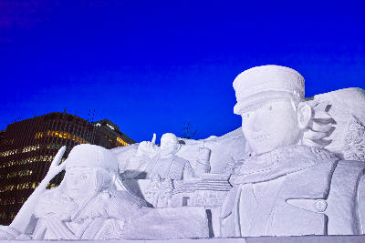 Large illuminated snow sculpture featuring anime characters at night during the Sapporo Snow Festival in Odori Park, Sapporo, Japan.