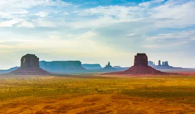 Monument Valley buttes viewed from Artist’s Point with wide desert plain and layered mesas under soft sunset sky